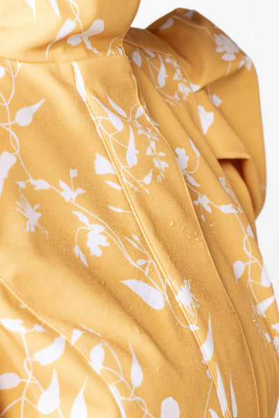 White floral pattern detail on bright yellow women's designer coat