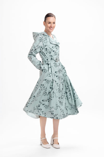 Model in motion wearing lightweight pastel green waterproof trench coat with elegant floral print