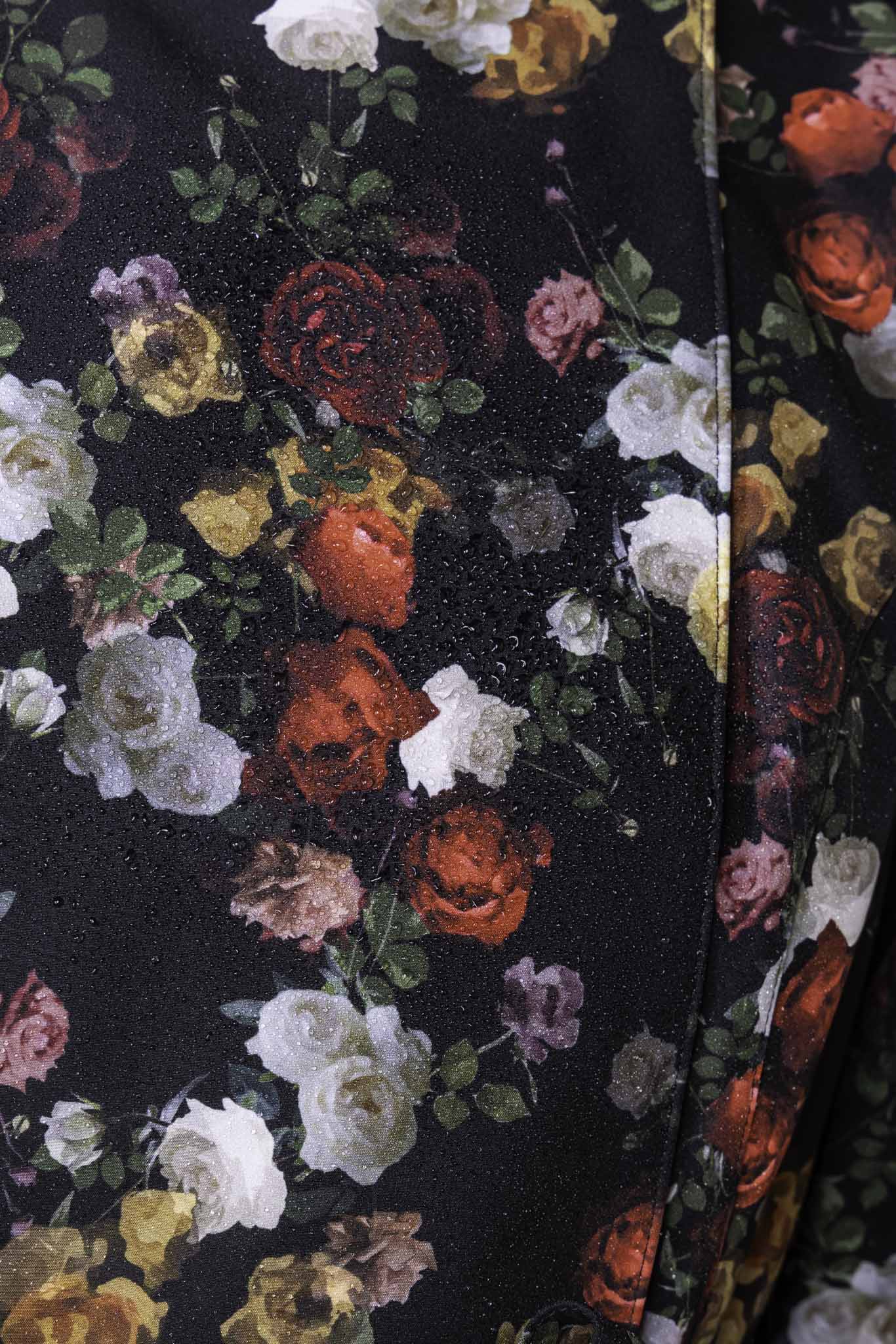 Close-up of red rose print on black fashion raincoat fabric by RainSisters