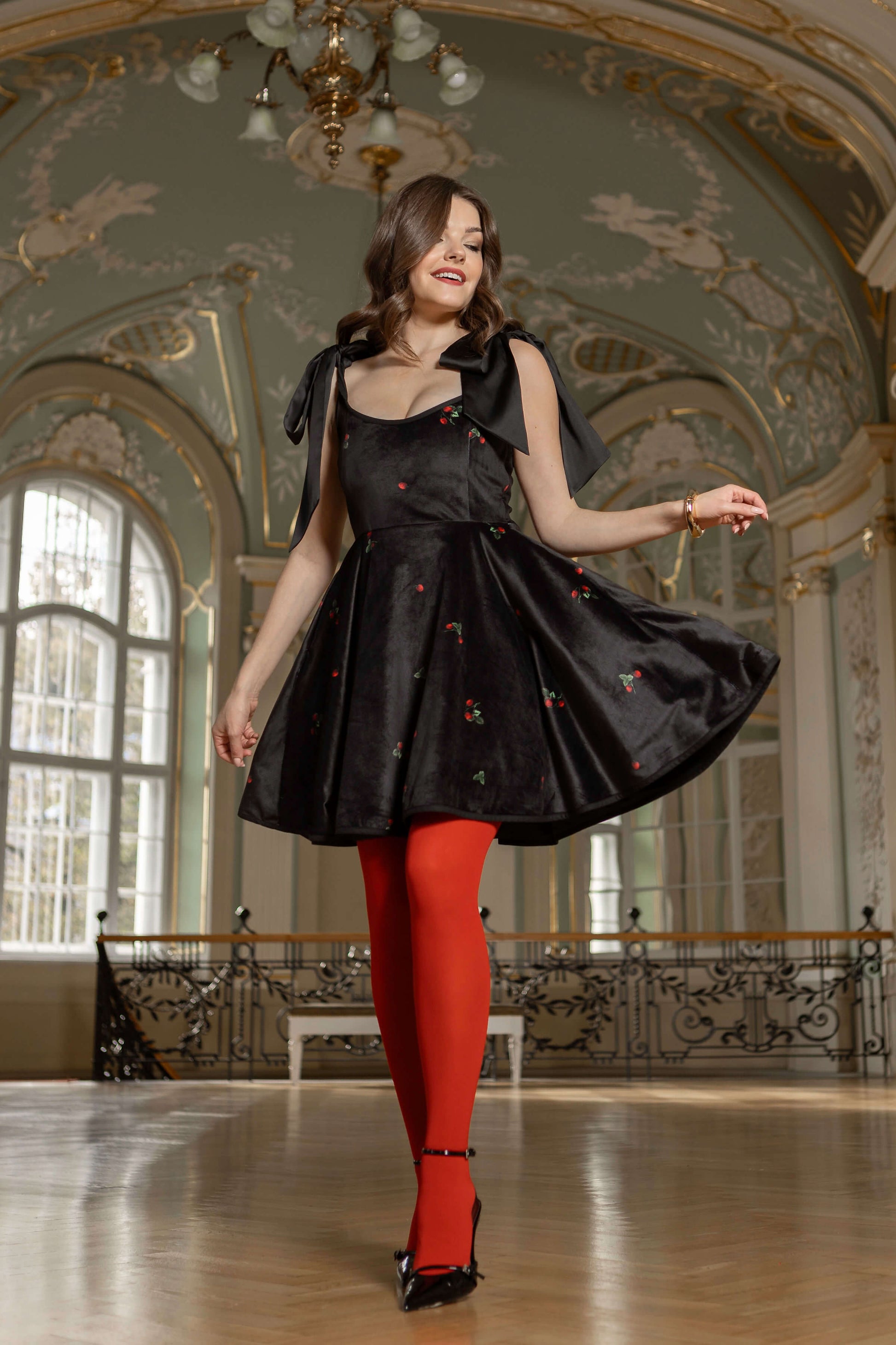 Black velvet Berry Swing dress with full-circle skirt, playful strawberry details, and romantic shoulder bows.
