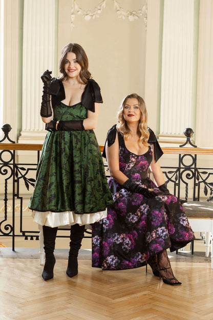 Green full-circle velvet dress with black floral design, discreet pockets, adjustable straps, and comfortable recycled polyester lining.