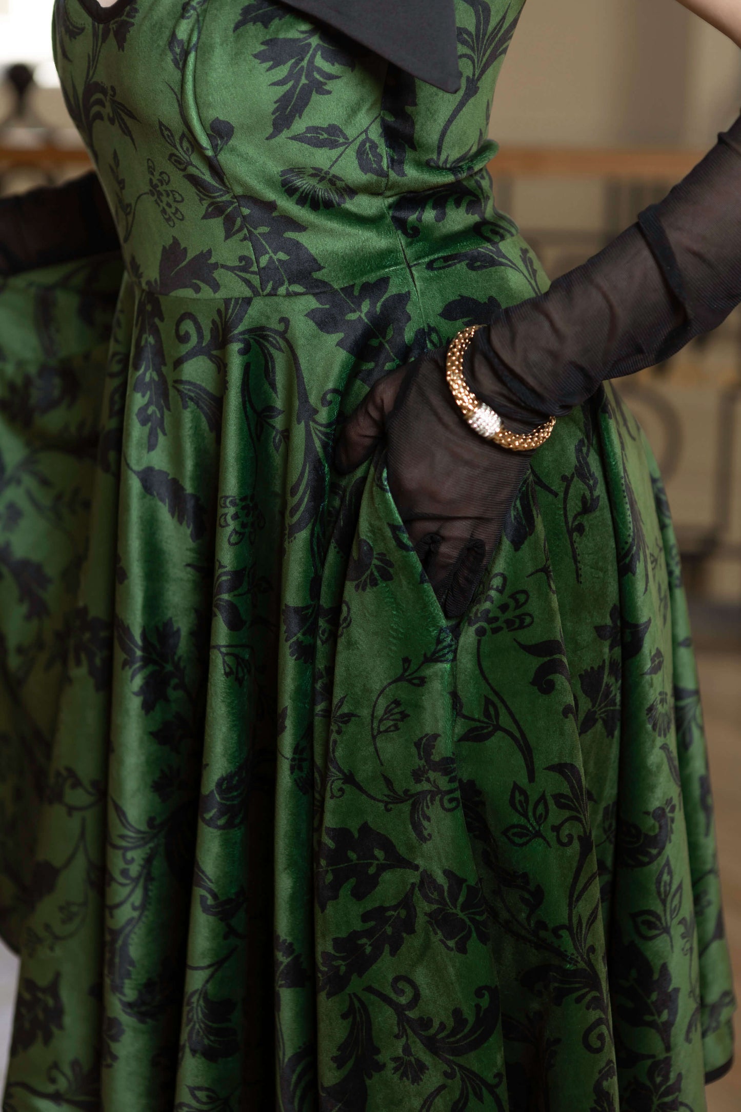 Forest Kiss full-circle velvet dress in green, featuring black floral print, side pockets, and elegant adjustable straps.