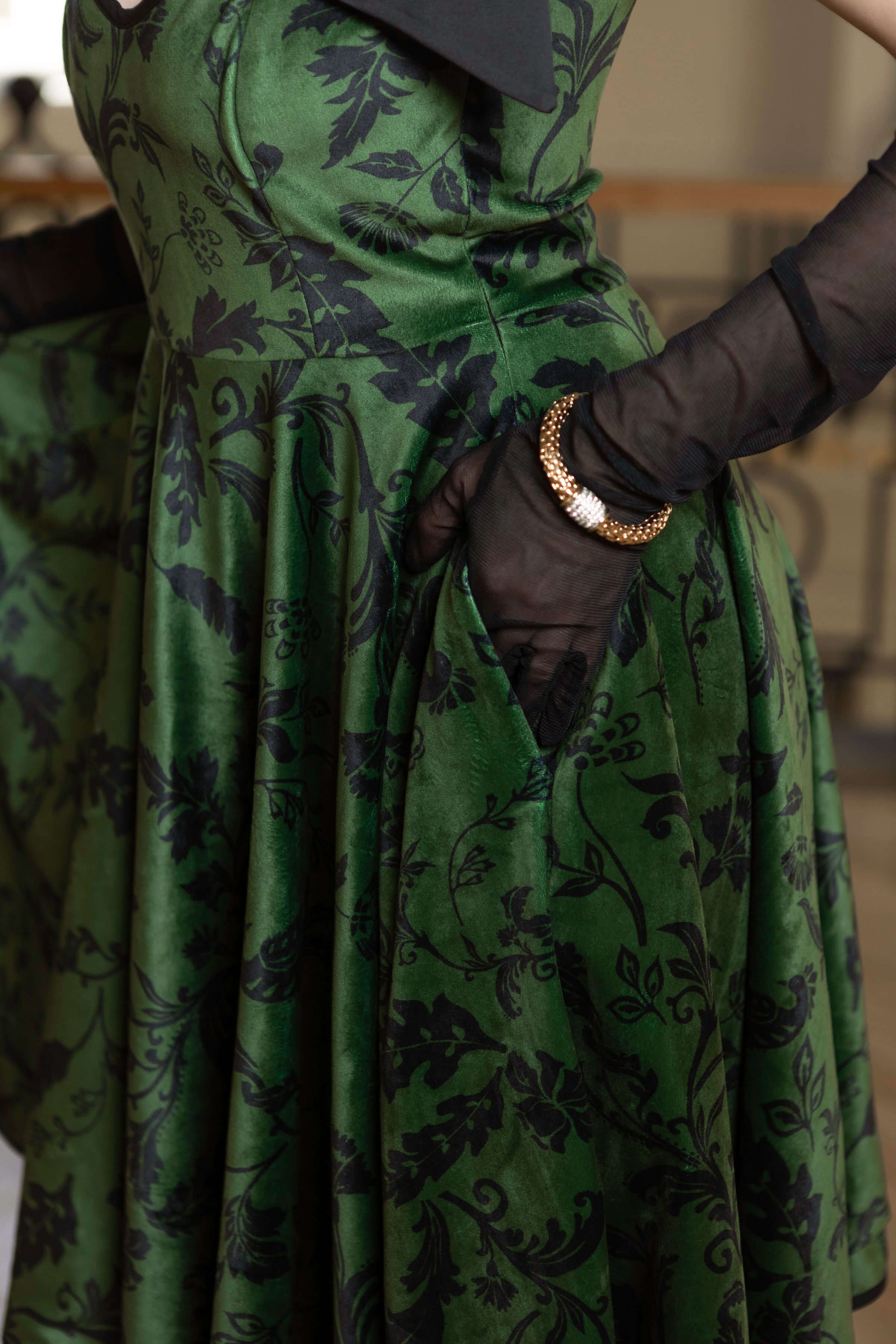 Forest Kiss full-circle velvet dress in green, featuring black floral print, side pockets, and elegant adjustable straps.