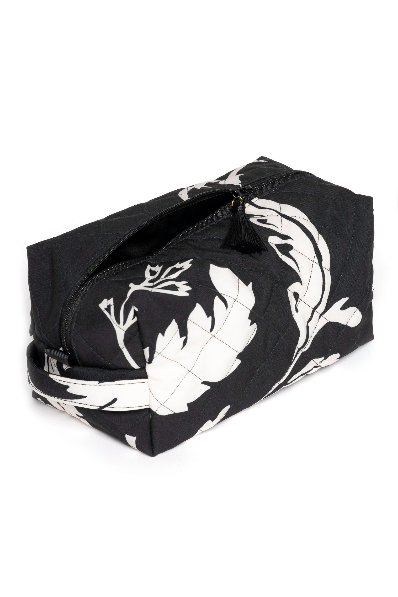 Large black travel makeup bag with white floral print opened to show black lining and spacious cosmetic storage compartment