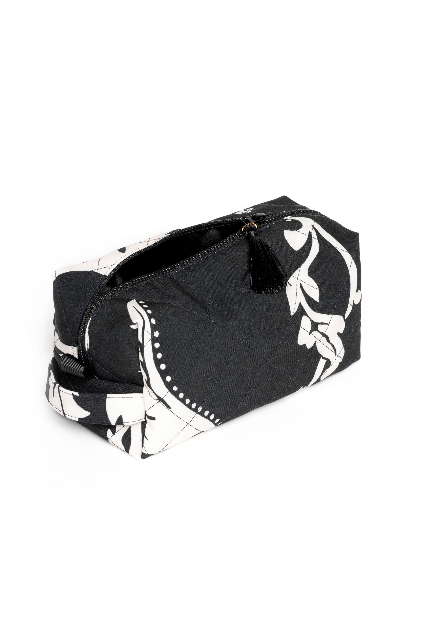 Small black makeup pouch with white floral print opened to reveal black lining and compact storage for beauty essentials