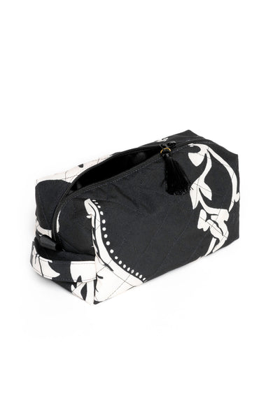 Small black makeup pouch with white floral print opened to reveal black lining and compact storage for beauty essentials