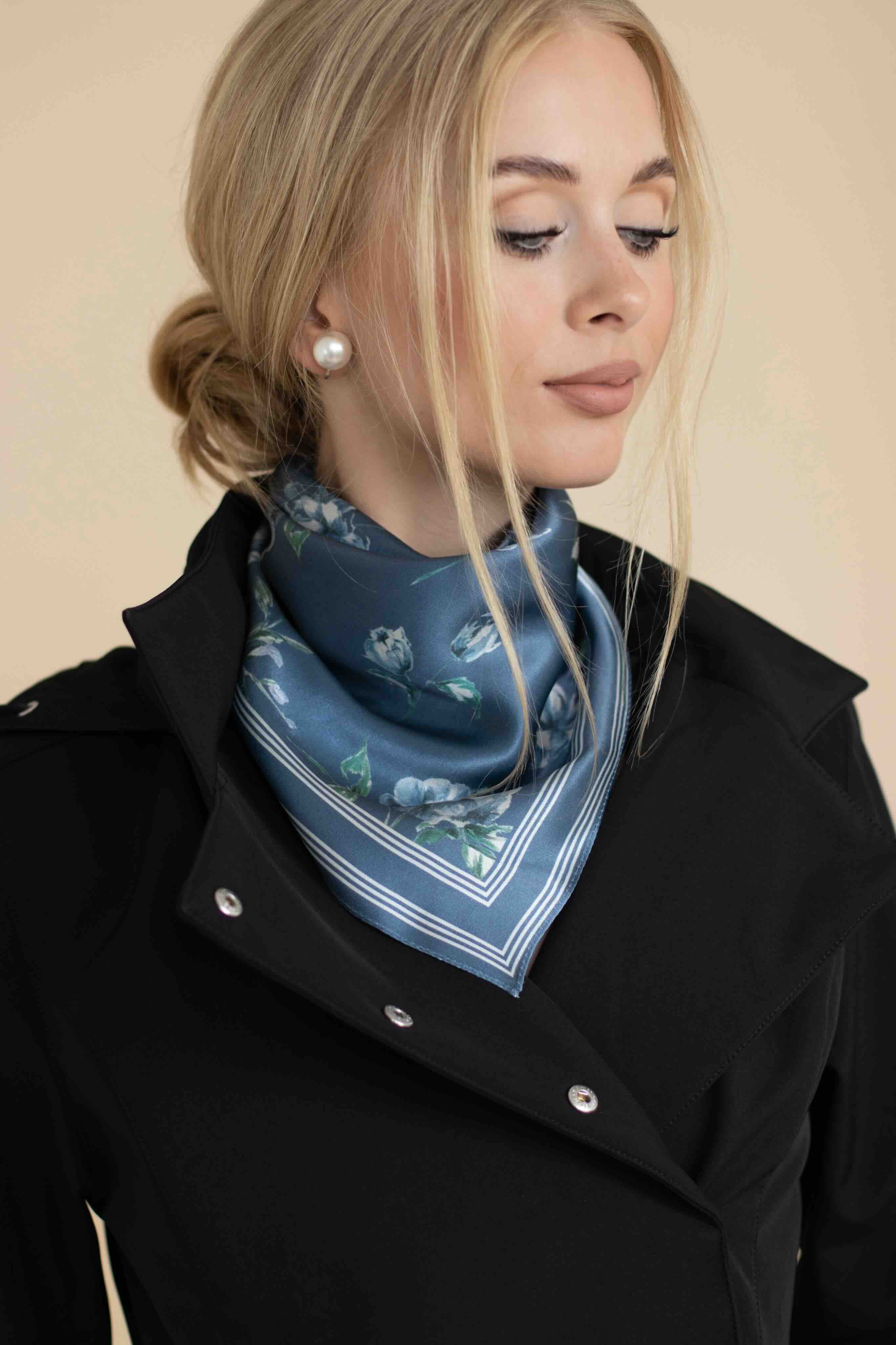 Woman wearing a blue patterned scarf around her neck against a beige background