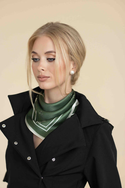 Woman wearing a green scarf and black coat against a beige background