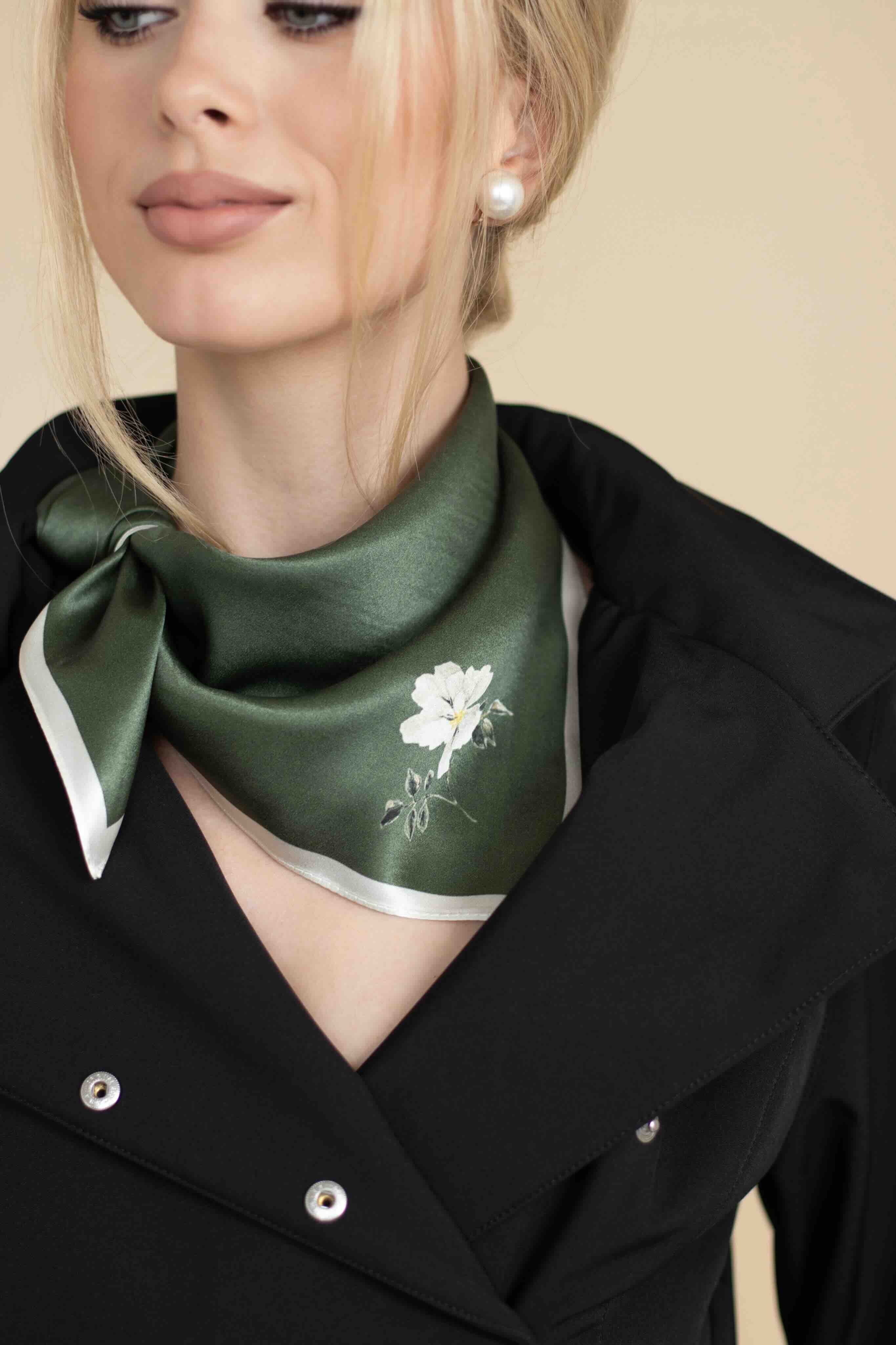 Woman wearing a green scarf with floral design around her neck against a beige background