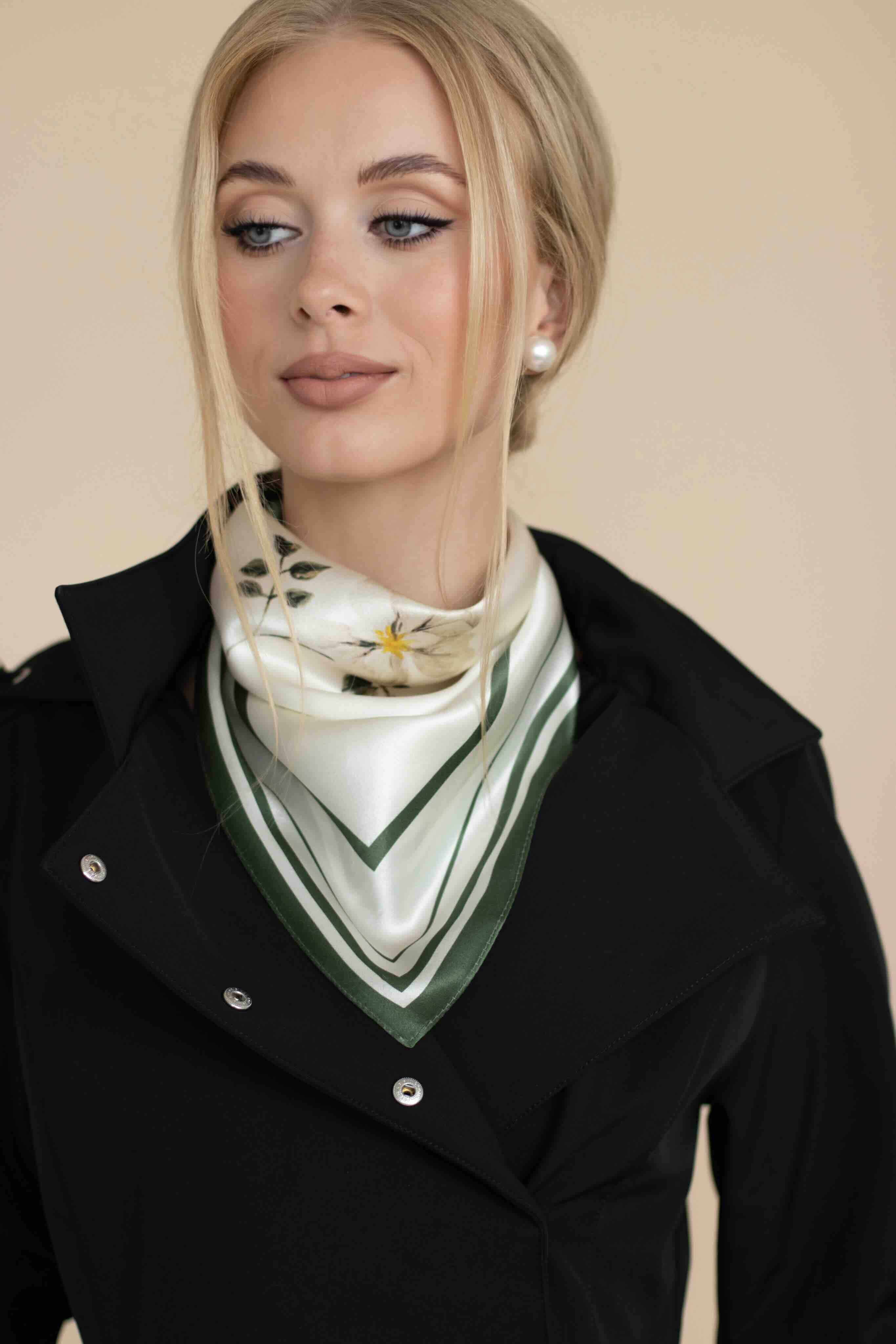 Woman wearing a black coat with a patterned scarf against a beige background