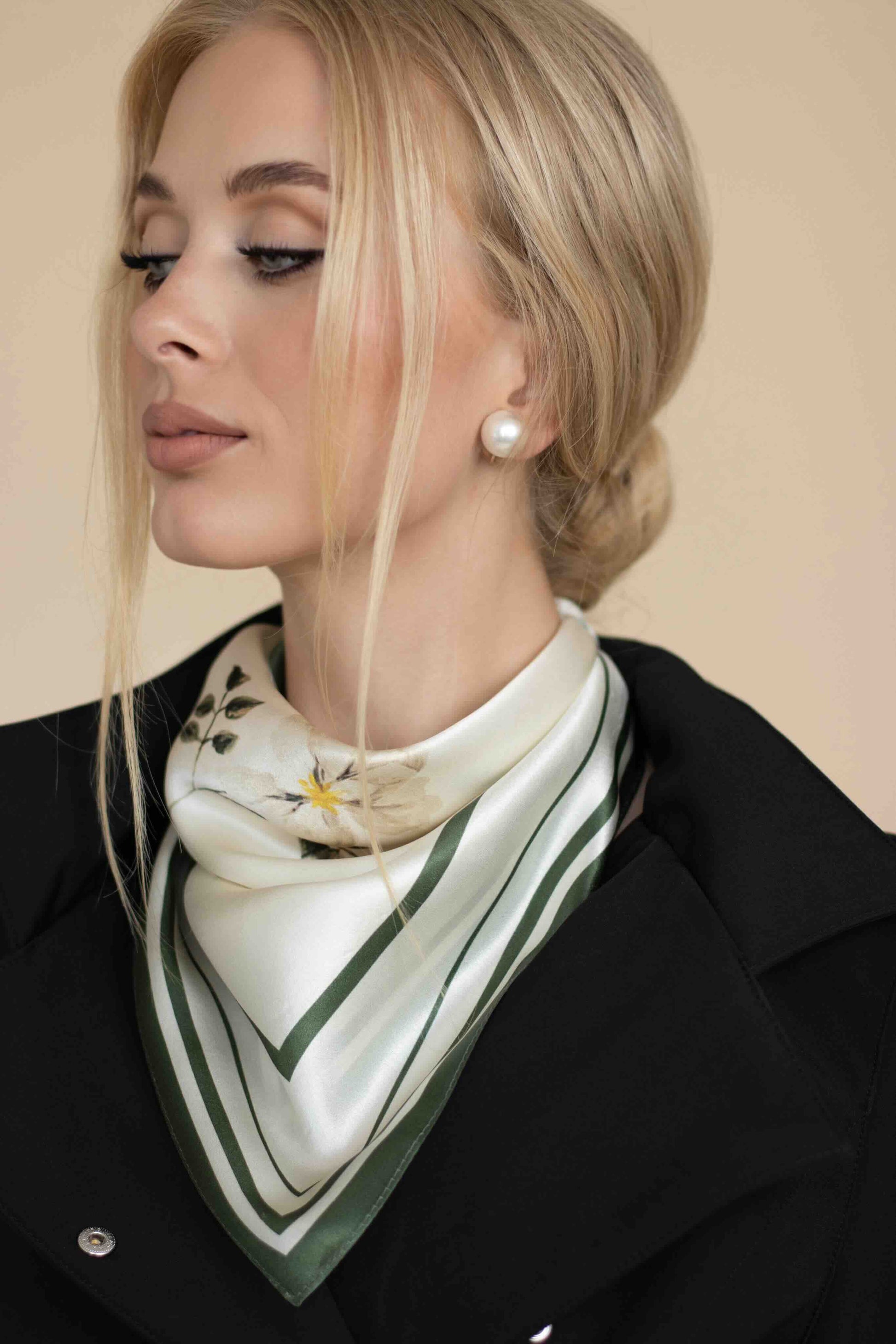 Woman wearing a green and white patterned scarf with a beige background