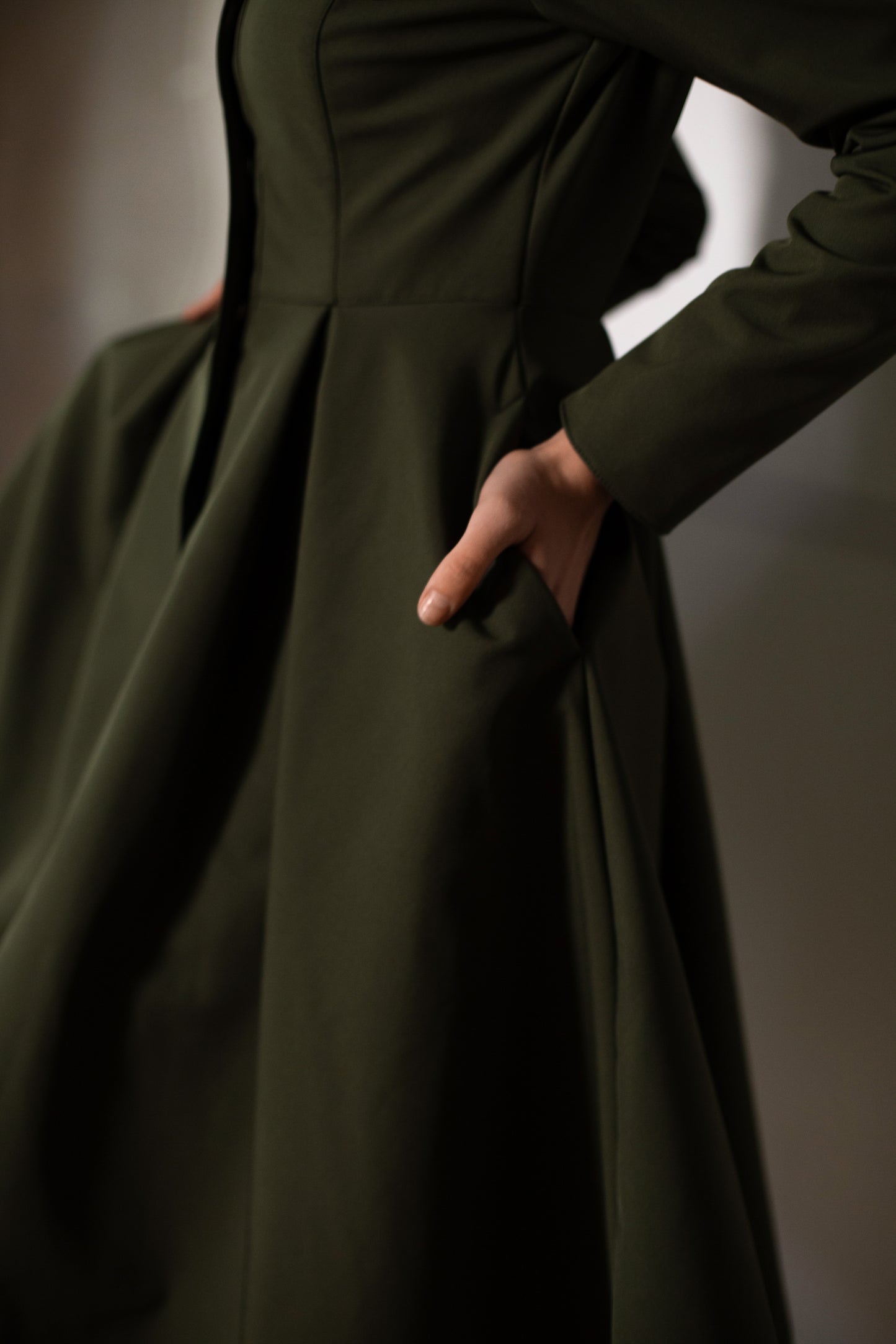 Khaki green waterproof coat with hidden pockets and pleated skirt